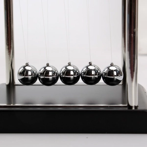 Close-up of five silver polished metal balls on a Newton's cradle with a black base
