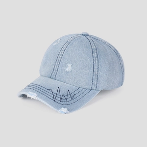 Macro shot of light blue denim baseball cap featuring distressed holes and wavy embroidery