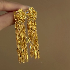 Détail des boucles d'oreilles rose dorée avec de longues pampilles en métal feuillé