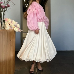Detail van roze chiffon top met ruches en witte satijnen maxi-rok op het model