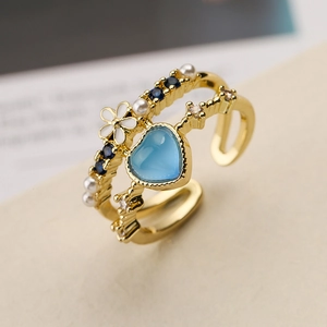 Macro detail of gold-plated open ring with heart gemstone, pearl and flower decor