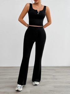 Detail of black yoga set featuring a buttoned sleeveless top and drawstring flared trousers
