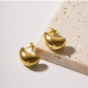 Detailed view of 18k gold plated crescent hoop earrings on a natural stone base