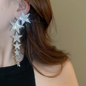 Macro detail of long silver star tassel earrings with sparkling crystals on a model