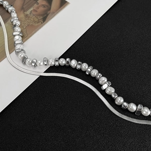 Detail of double-layer necklace with silver snake chain and irregular white pearls