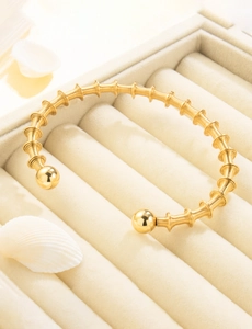 Detail of 18K gold plated spring coil bangle with round beads in a velvet jewelry box