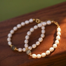 Close-up of fresh water pearl bracelets with grey stone on dark wooden background