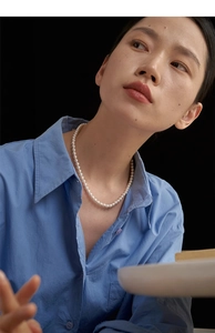 Close-up of a vintage pearl beaded necklace on a model wearing a blue cotton shirt