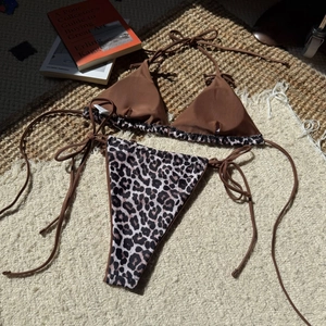 Close-up of leopard print bikini bottoms and brown top on textured woven carpet