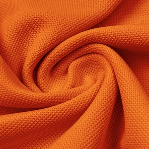 Close-up of orange waffle knit fabric texture showing breathable moisture-wicking weave
