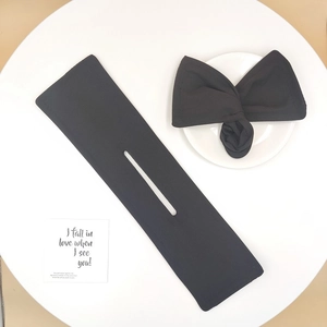 Close-up of black bow hair bun maker tool and a finished floral hairstyle on white table