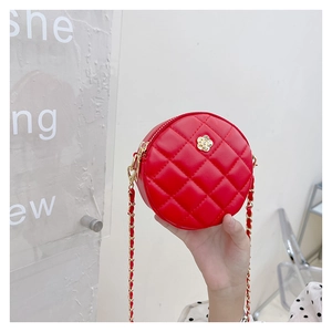 Macro view of red quilted round crossbody bag featuring golden flower metal hardware