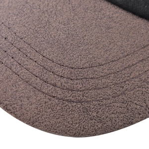 Macro detail of brown cotton baseball cap visor showing triple stitching and texture