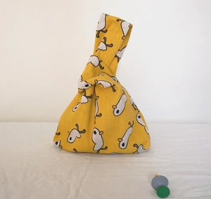 Detail of yellow cotton linen wrist bag with white animal prints and knotted handle strap