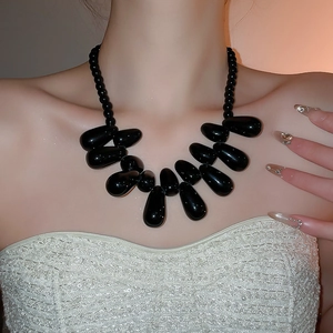 Détail d'un collier bohème avec pendentifs gouttes noires porté par un mannequin