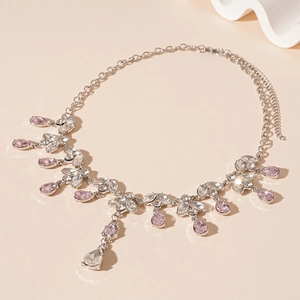 Collier feuille en argent avec pampilles en cristal rose et strass sur un fond beige doux