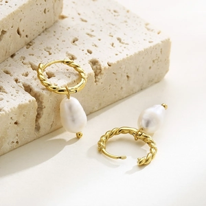 Detail of golden twisted rope earrings with irregular baroque pearl drop on stone