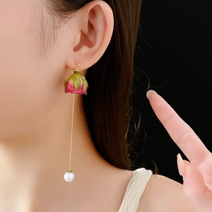 Détail de boucles d'oreilles rose éternelle avec chaînes fines et perles blanches