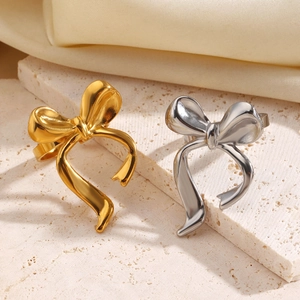 Elegant bow-shaped open rings in gold and silver finish on a white stone background