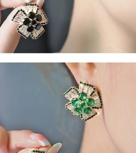 Close-up of sparkling cubic zirconia flower earrings in black and green colors