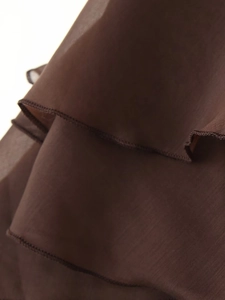 Dettaglio del tessuto in chiffon marrone scuro con volant a strati e cuciture fini