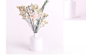 Detailed view of matte white ceramic diffuser bottle with dried flowers and black fiber sticks