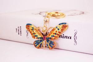 Detail of colorful crystal butterfly keychain with golden metal base on a white book