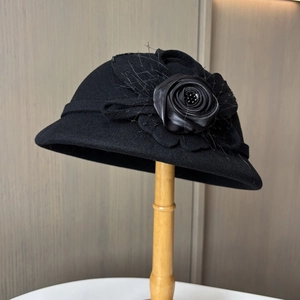 Nahaufnahme von schwarzem Wollglockenhut mit Seidenrose, Netzschleier und Perlendetails