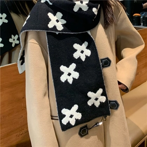 Knitted winter scarf with black and white floral pattern worn over a camel coat