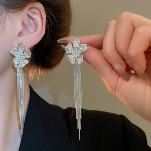 Detail of 18k gold plated silver earrings featuring floral pearl and long tassel chains