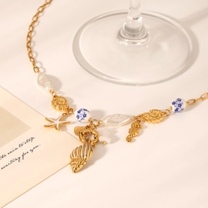 Detail of gold ocean charms including starfish, seashells, and pearls on a sleek necklace