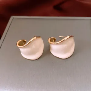 Minimalist C-shaped gold plated wave earrings with cream enamel finish and silver studs