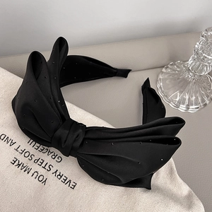 Detail of elegant black satin headband with polka dots and large bow on canvas bag