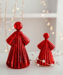 Detail of two red glass angel figurines with vertical ribbed texture and warm bokeh lighting