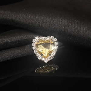 Macro shot of heart-shaped yellow crystal with white rhinestone halo on black silk