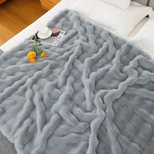 Detail of light gray faux rabbit fur blanket with thick wavy texture on a bed