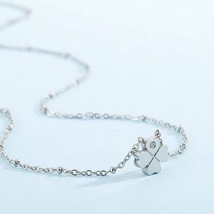 Silver stainless steel four-leaf clover necklace with transparent gemstone on blue background