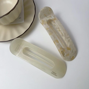 Detail of premium acetate hair clip set in cream and marble finish with French logo
