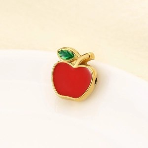 Macro detail of red enamel apple charm with gold finish for bracelet and necklace