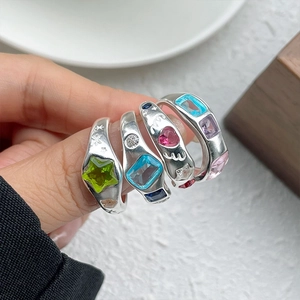 Detail of four stacked 925 silver rings with colorful star, heart, and rectangle crystals