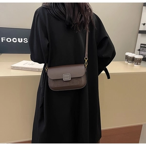 Brown vintage leather crossbody bag with square buckle worn with a black wool coat