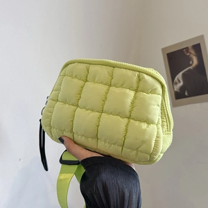 Close-up of neon green quilted crossbody bag with puffer lattice texture and wide strap