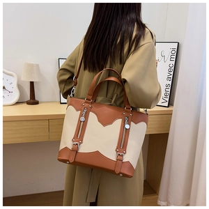 Detail view of large faux leather tote bag with contrasting colors shown in lifestyle setting