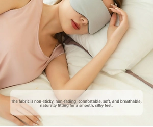 Close-up of a breathable gray silk sleep mask on a model resting on white bedding