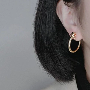 Close-up of golden twist hoop earring worn on ear with elegant metallic luster