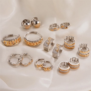 Elegant twist heart stud earrings and rhinestone hoop set on white satin fabric