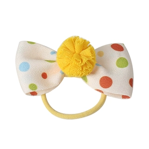 Cute beige fabric hair bow with colorful polka dots and a yellow pom-pom center