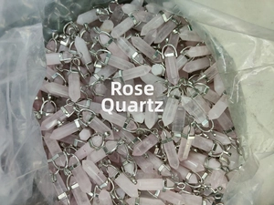 Bulk lot of rose quartz hexagonal prism pendants with silver metal clasps in storage