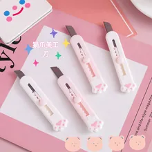 Detailed view of four cute cat paw utility knives in pink and white on a creative desk background