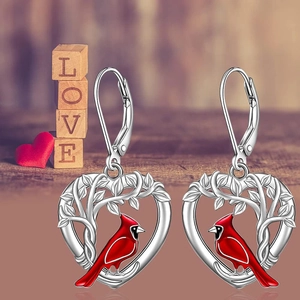 Detail of heart-shaped silver earrings with red cardinal bird and leaf pattern